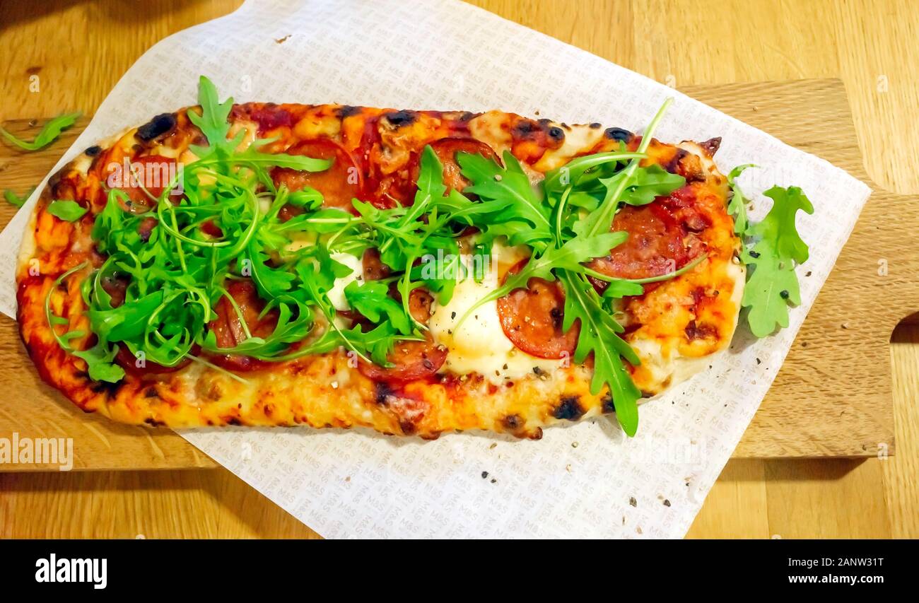 Pizza with pepperoni mozzarella cheese rocket and tomatoes served on a