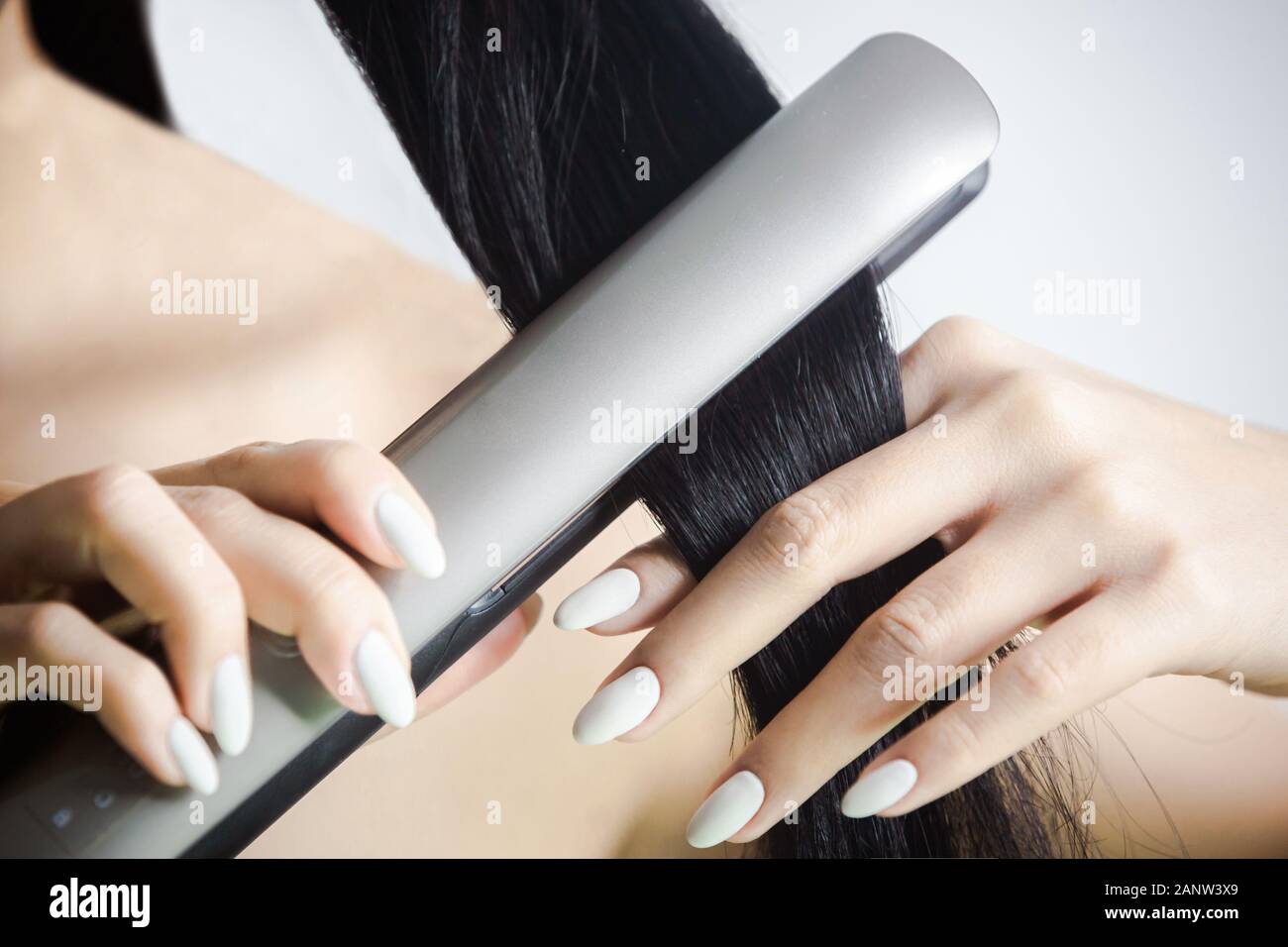woman straightening her hair with hair iron Stock Photo