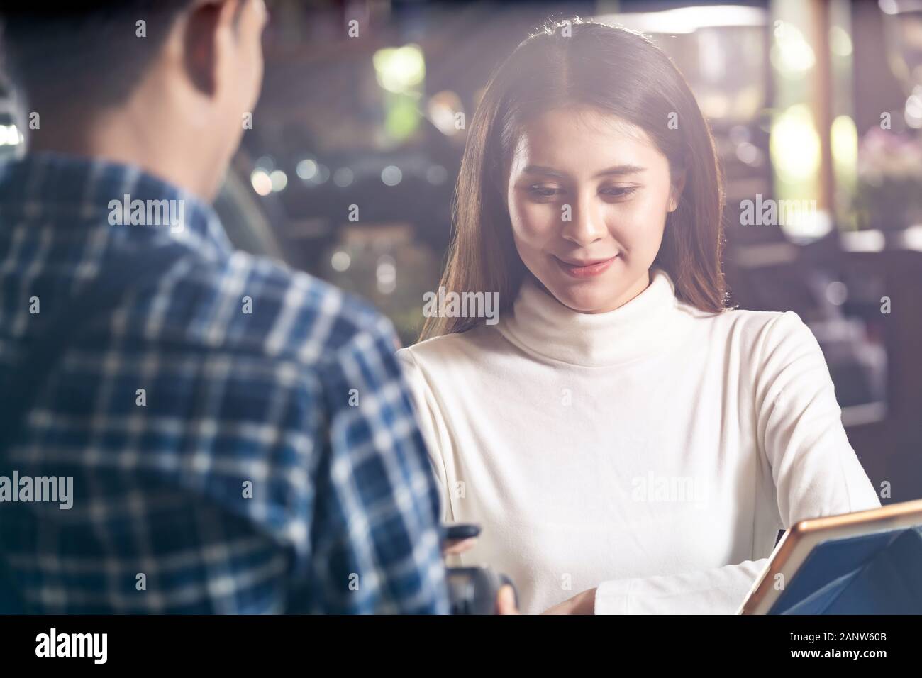 Asian woman customer using mobile phone scane QR code on credit card reader EDC machine to pay a waiter for coffee purchase at table in cafe. Stock Photo