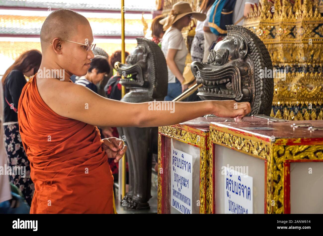 BANGKOK, THAILAND – DEC. 23, 2018: Unidentified Buddhist monk offering money in donation box in the Temple of the Emerald Buddha (Wat Phra Kaew). Stock Photo