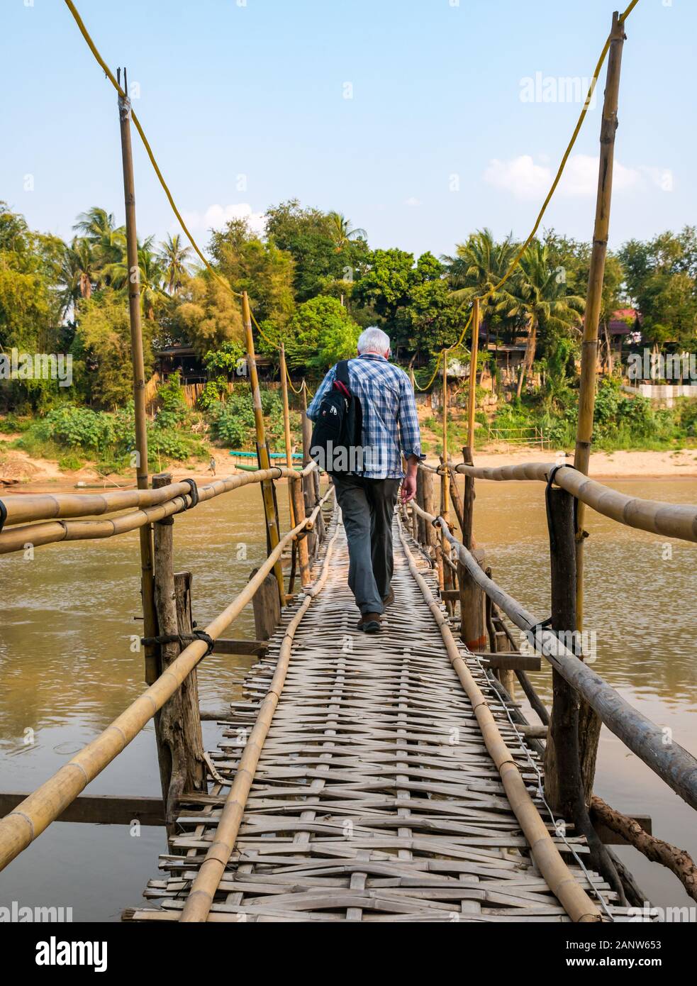 Senior male man tourist walking on rickety bamboo bridge, Nam Khan river, Luang Prabang, Laos Stock Photo