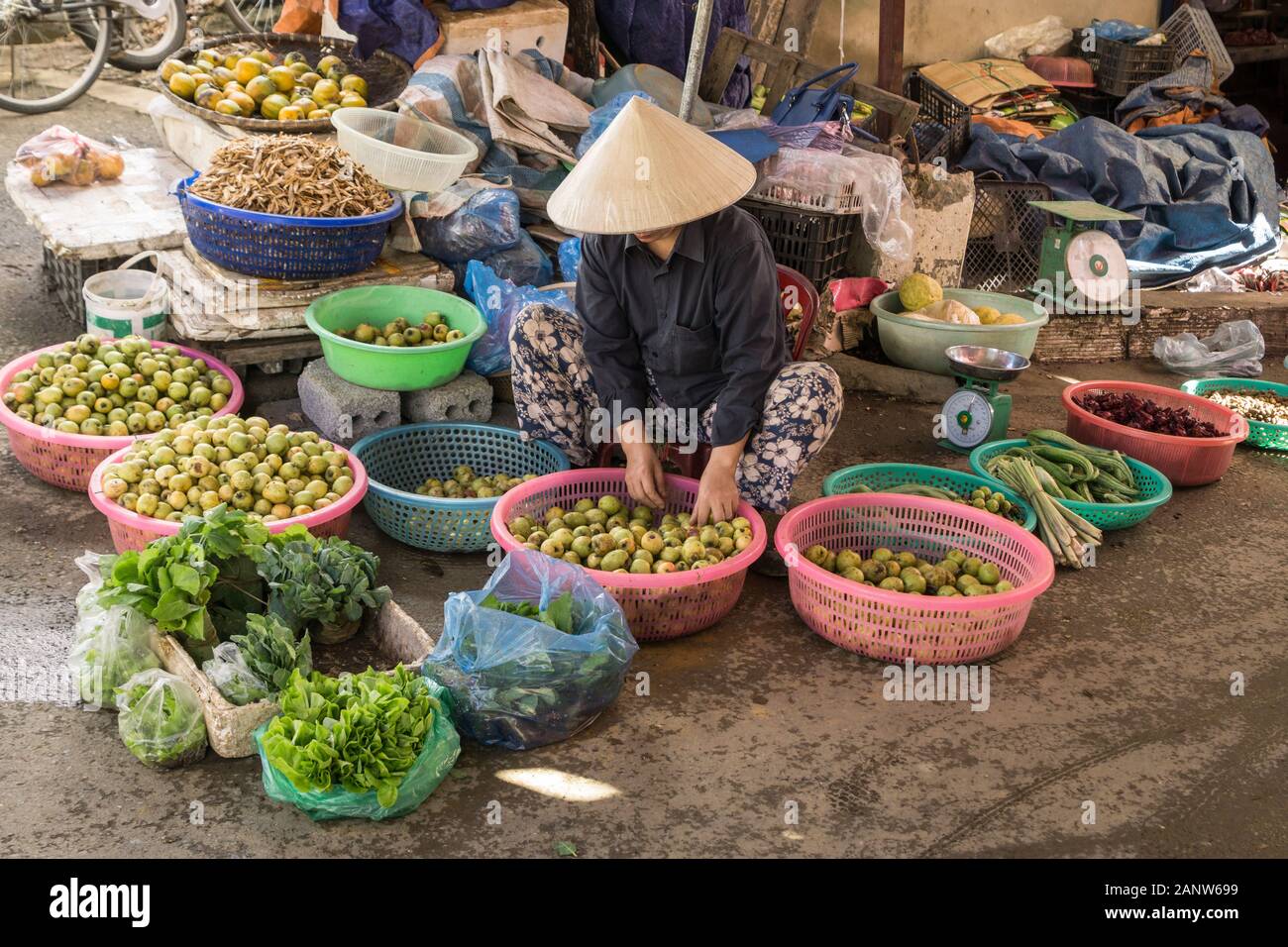 A vietnamese lady sitting on a street corner selling her fresh fruit and greens. Photo taken in Lai Chau, Vietnam Stock Photo