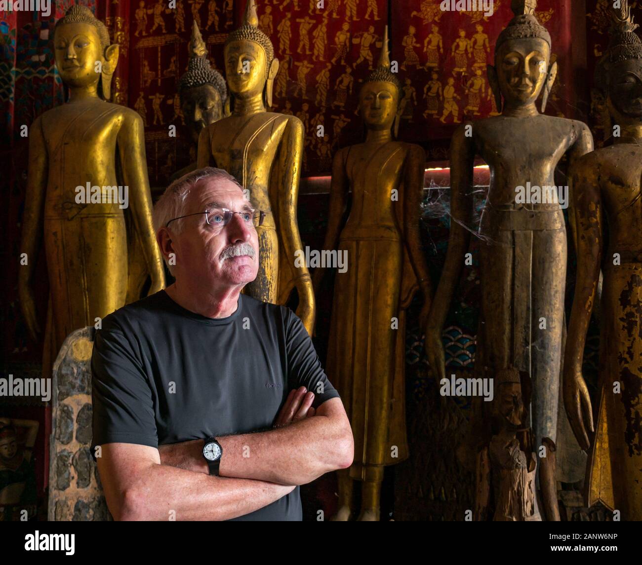 Senior male man tourist admiring Wat Xien Thong temple figures, Luang Prabang, Laos, Southeast Asia Stock Photo