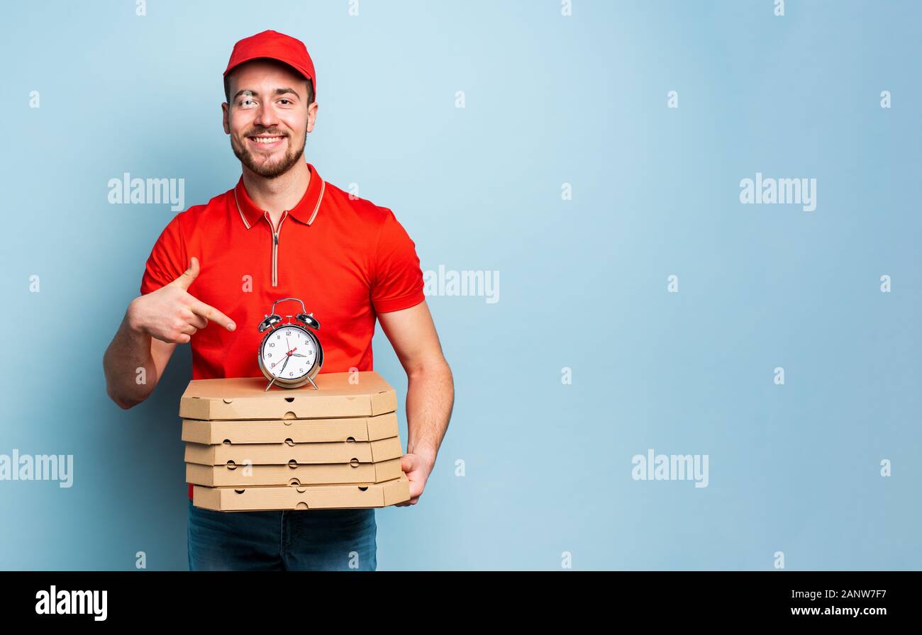 Deliveryman is punctual to deliver quickly pizzas. Cyan background Stock Photo