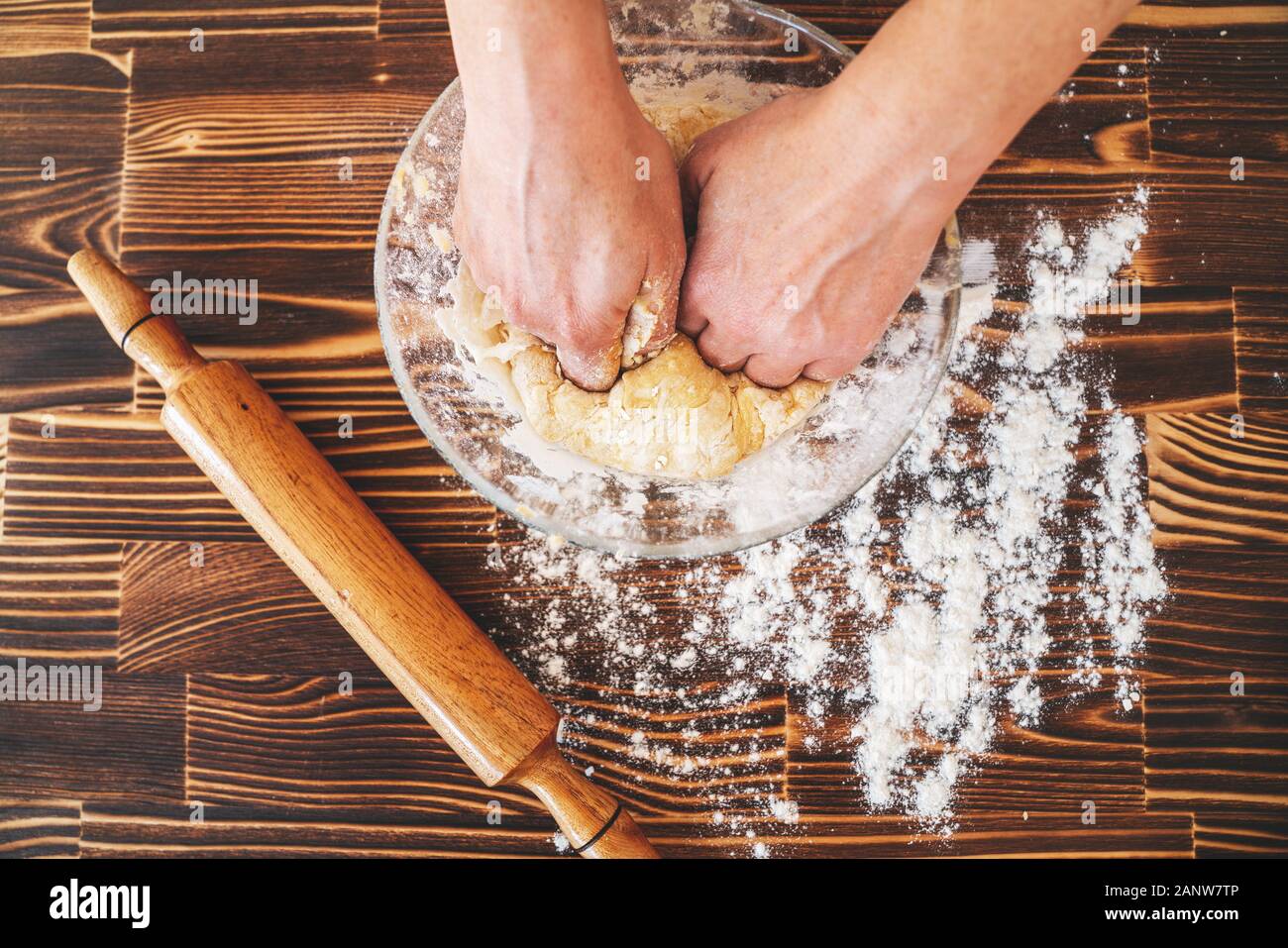 Woman is kneading dough in kitchen, dough recipe ingredients and rolling pin on vintage wood