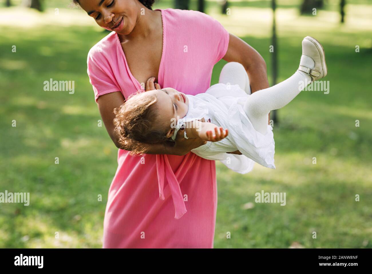 Mother playing with daughter in the park carry her on hands Stock Photo