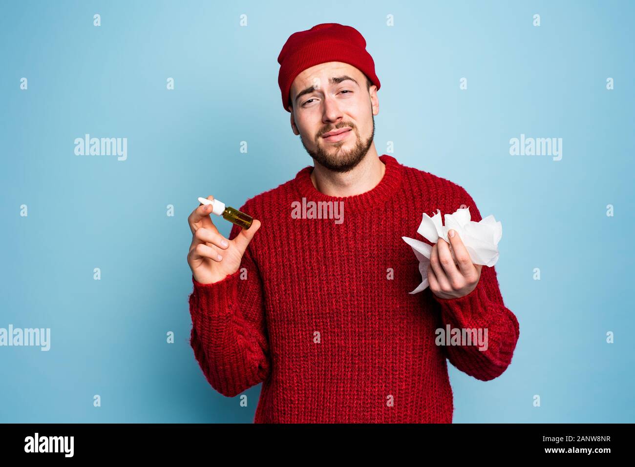 Boy caught a cold and uses spray to heal. Studio on Cyan background Stock Photo