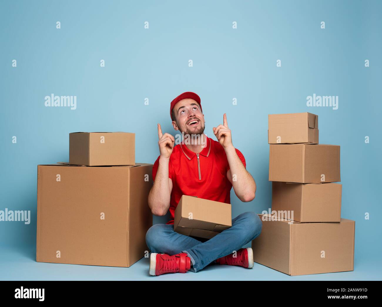 Courier is happy and indicates something above. Studio on cyan background Stock Photo