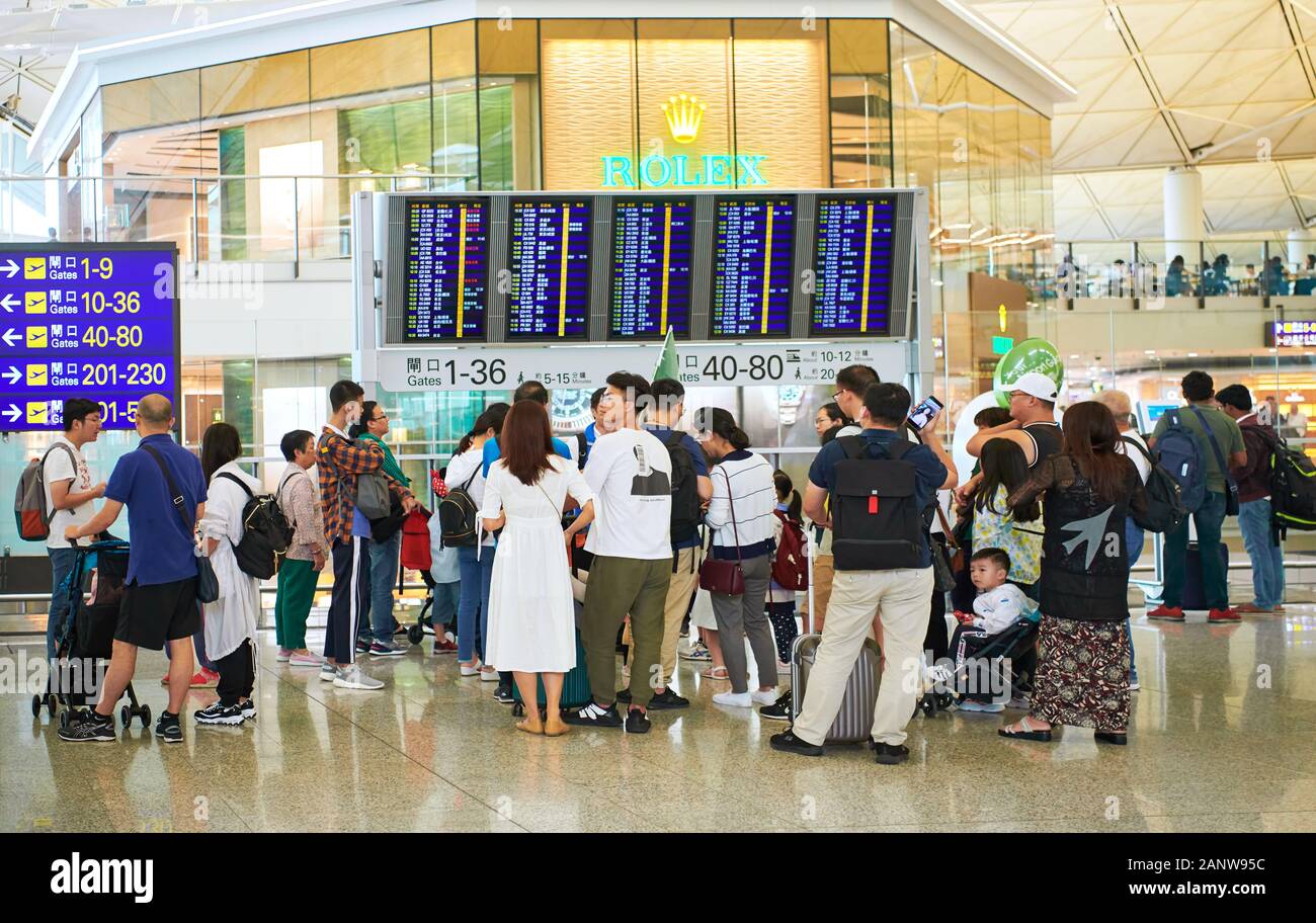 Hong Kong: A group of chinese tourists with a tour guide in front of the information board inside Hong Kong International Airport Stock Photo