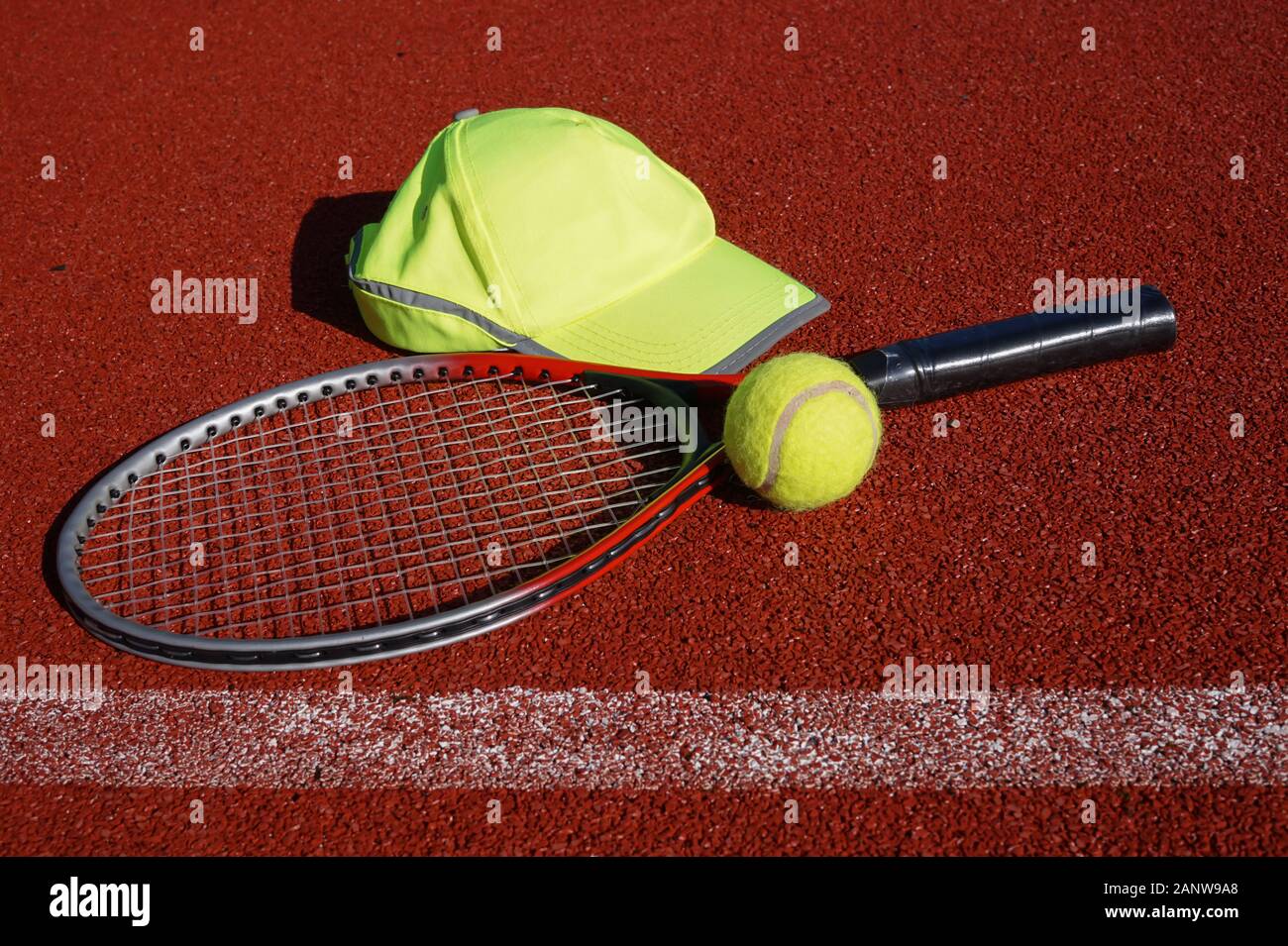 Tennis racket on all weather outdoor court, peaked cap and balls in a ...
