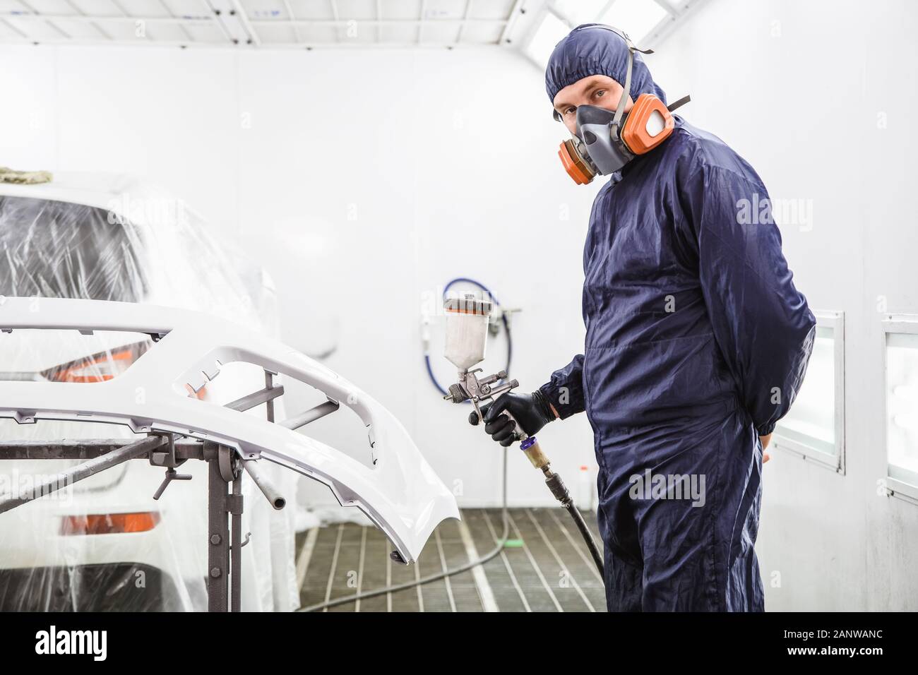 worker in overalls with a respirator and spray gun in his hand in the