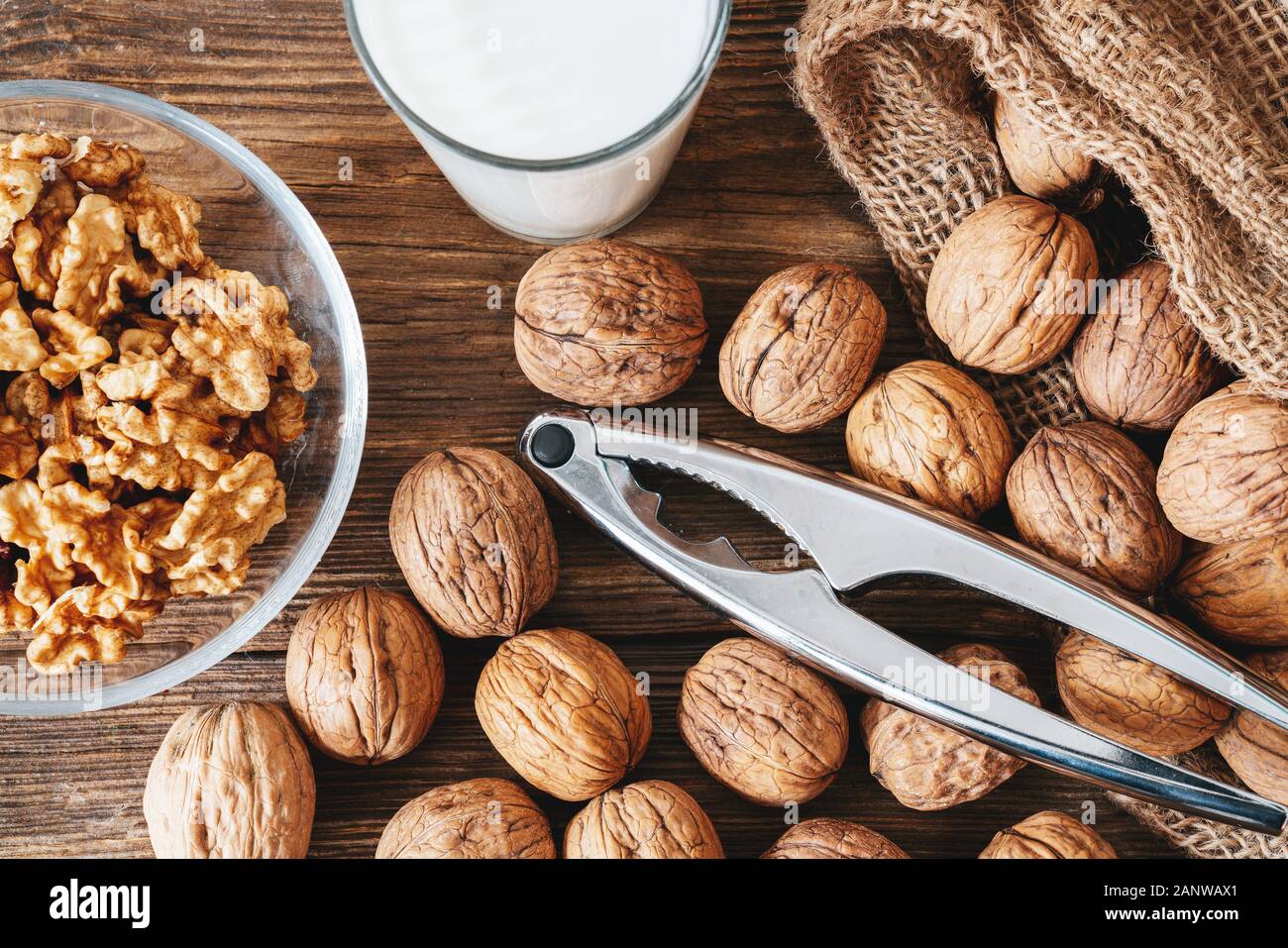 whole walnuts in a cotton bag, scattered nuts on a wooden table. Walnut kernels in a bowl. Stock Photo