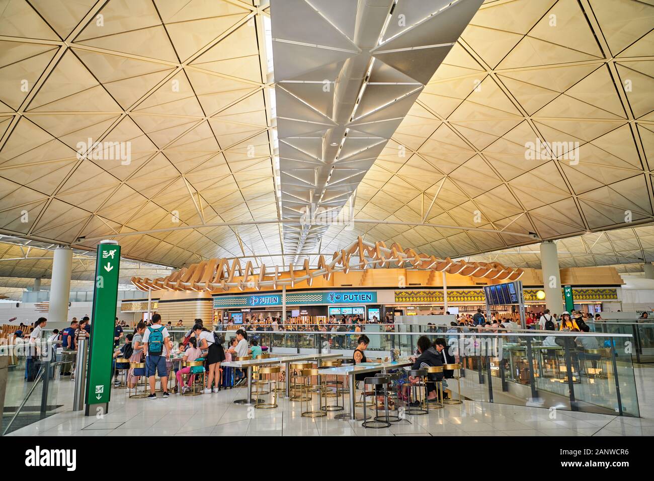 Hong Kong: Tourists at restaurants in the transit area inside Hong Kong International Airport with its futuristic architecture Stock Photo