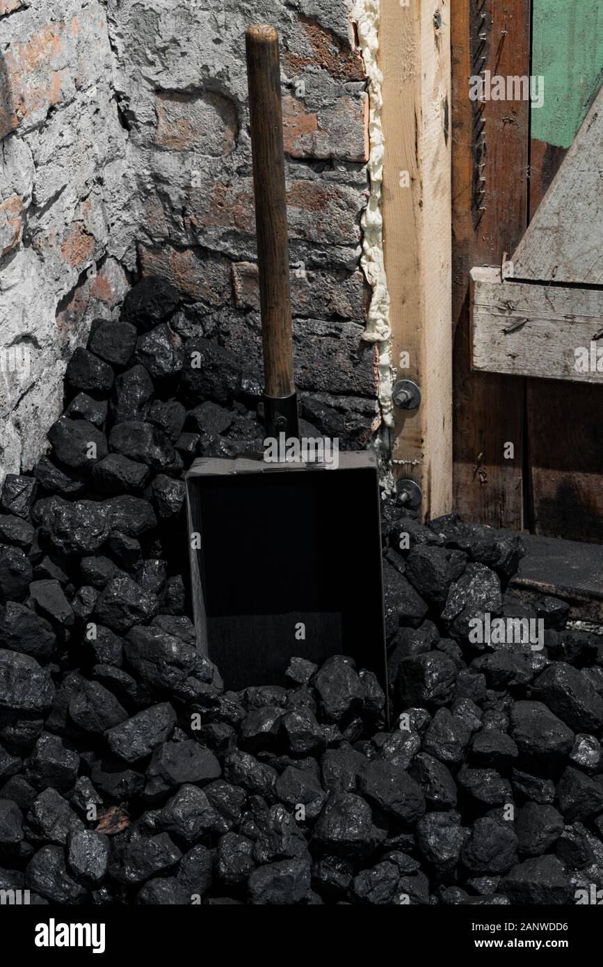 A coal shovel stuck in a pile of coalat the basement prepared for heating the house with. Stock Photo