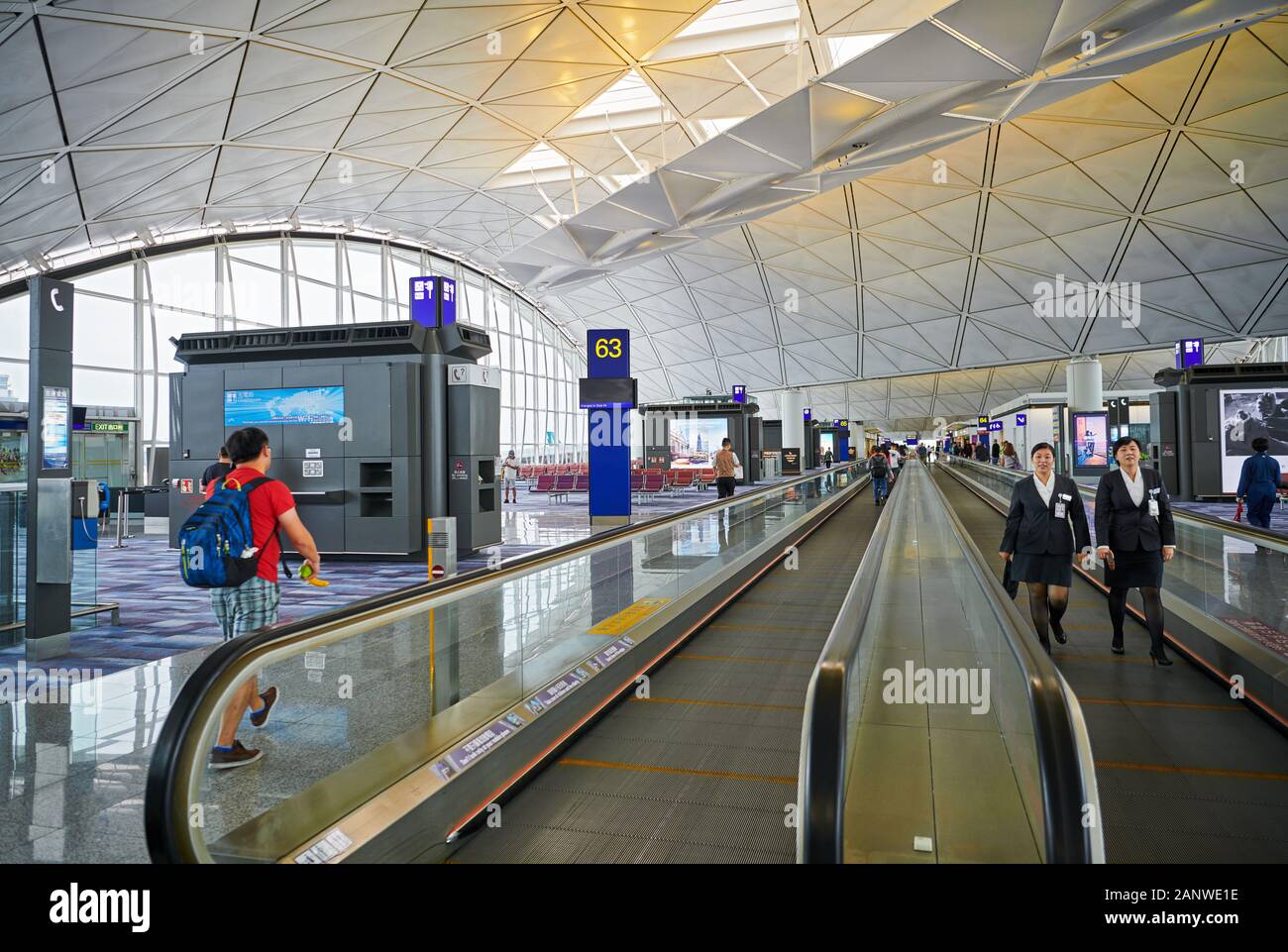 Hong Kong: View of modern looking departure area with two women personnel using escalators inside Hong Kong International Airport Stock Photo