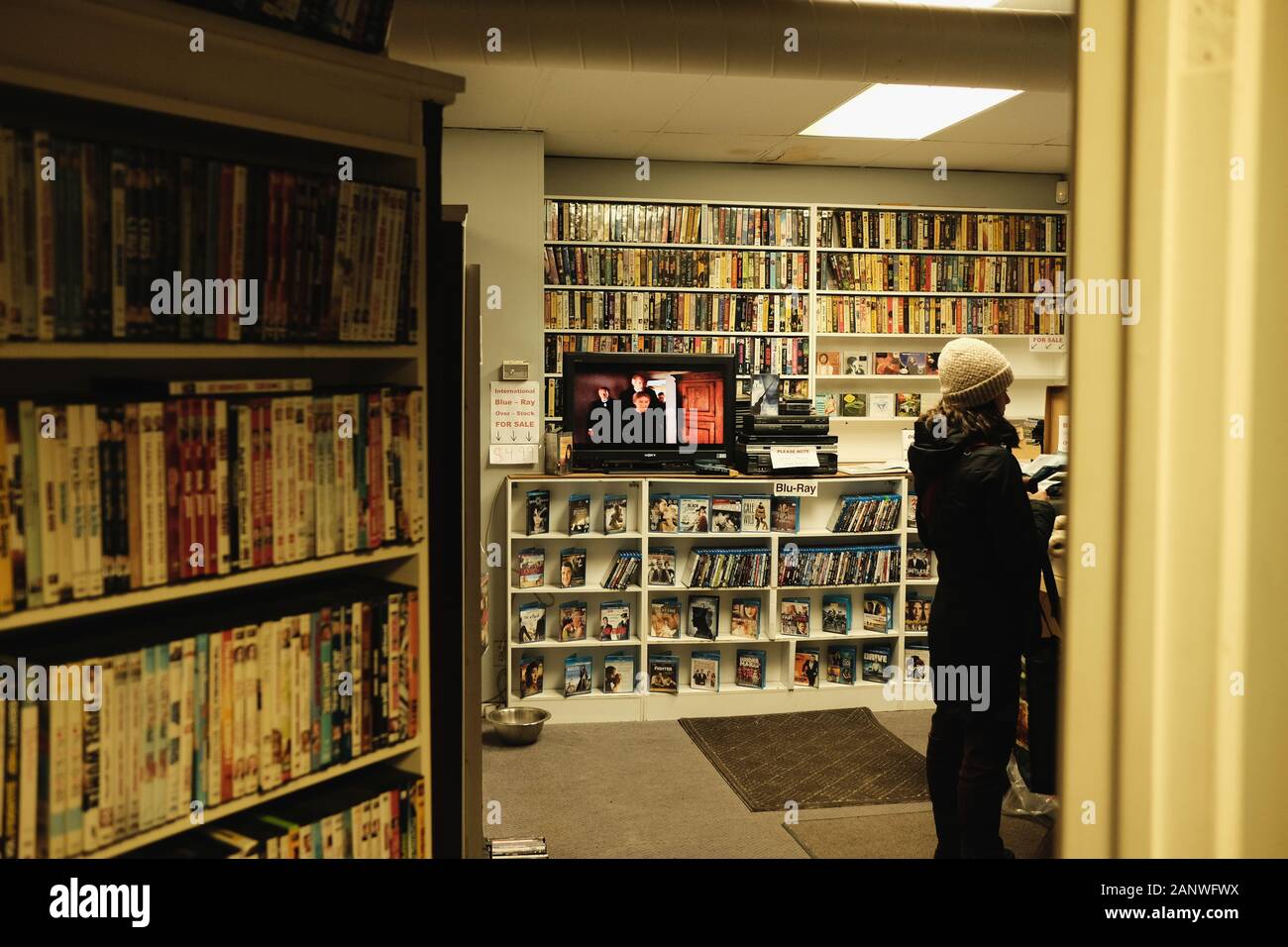 A shopper queues to rent a DVD at local video rental store, Glebe Video