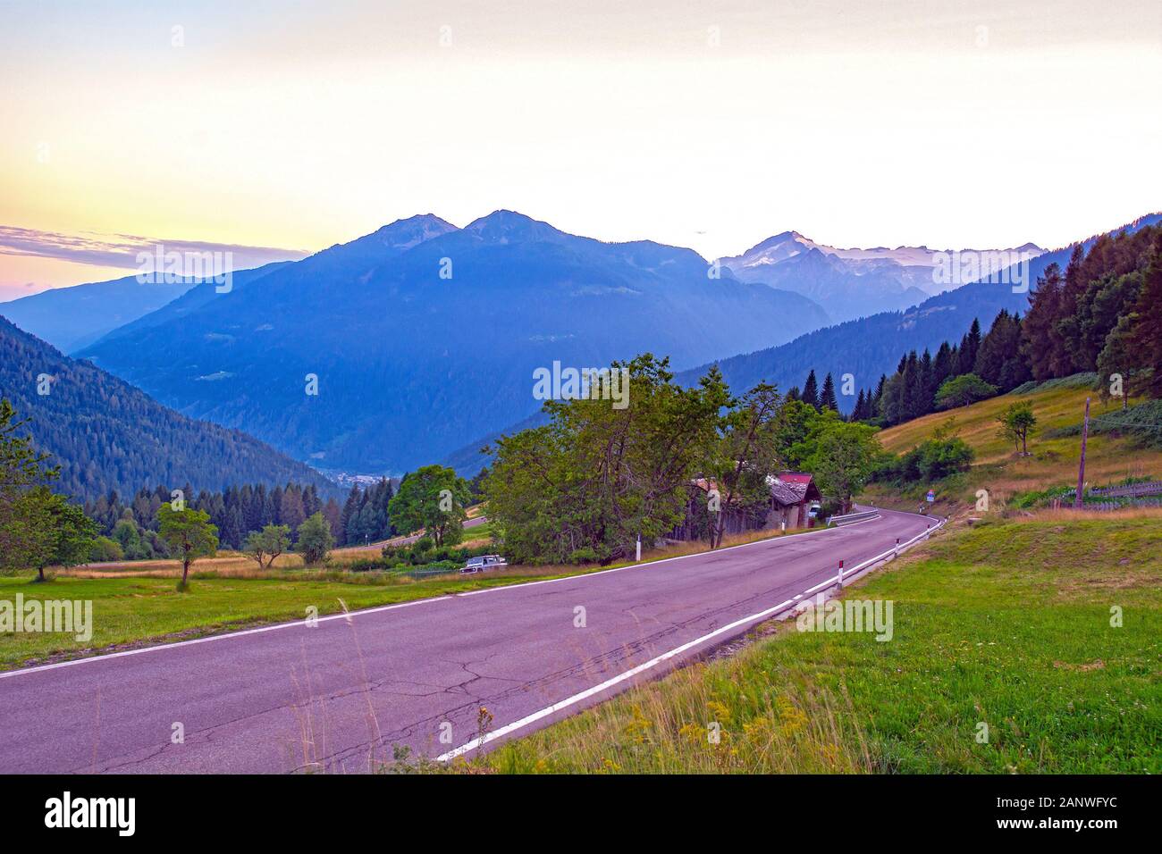 Mountain road by dusk in Italian Brenta Dolomites Alps, Pinzolo down in valley Val Rendena - Madonna Di Campiglio above Stock Photo