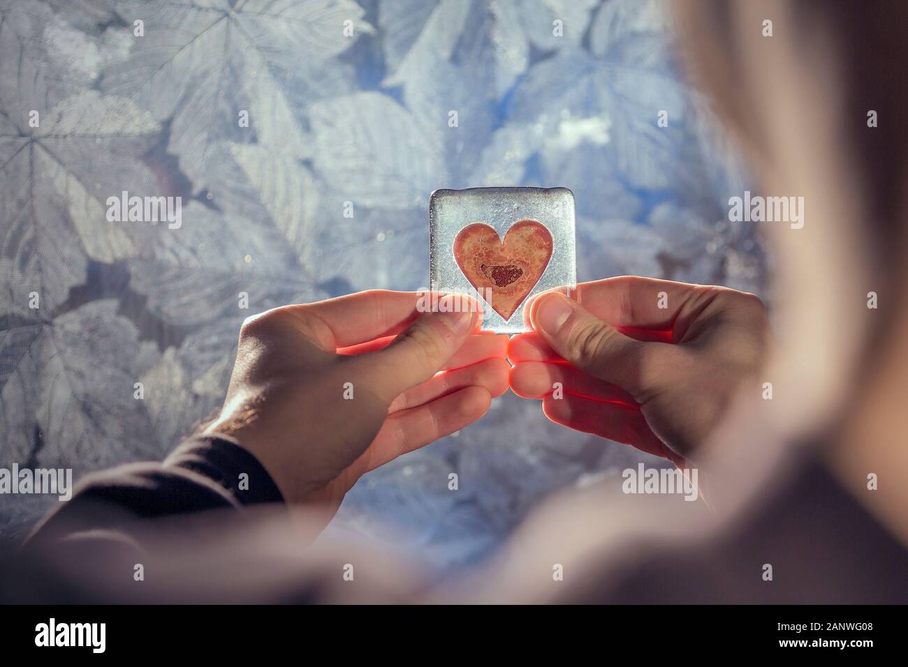 A young man holds a heart shaped object, conveying a range of emotions such as love, longing, loneliness and infatuation. Stock Photo