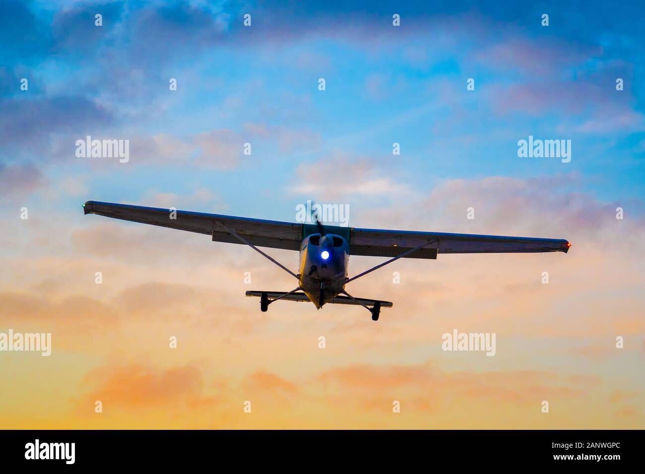Shot of a silhouetted, unidentifiable private aircraft on final approach for landing as the sun sets. Stock Photo