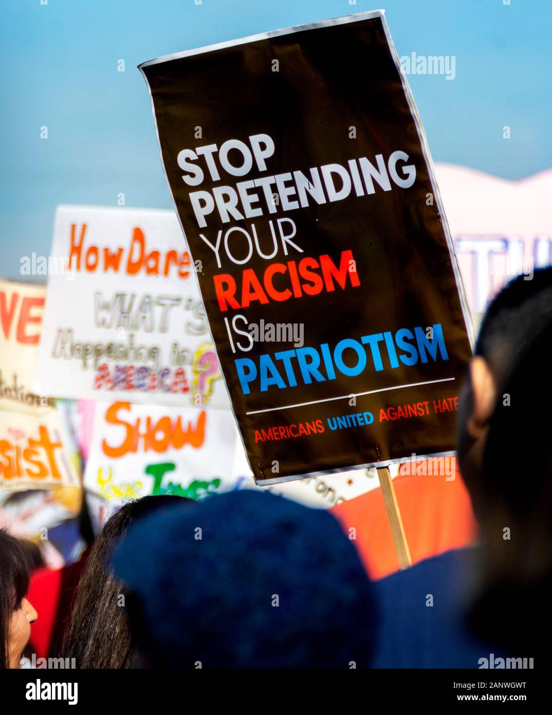 Group of activists at the OC Women’s March with protest signs. One reads, “Stop Pretending Your Racism is Patriotism. Americans United Against Hate.' Stock Photo