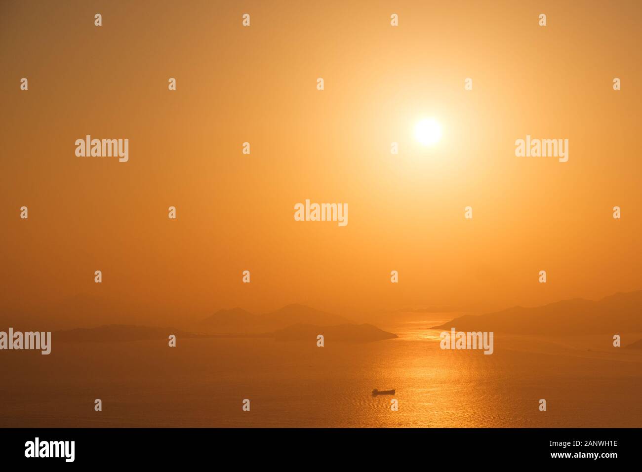 tanker ship on ocean horizon with sunset sky and coast background Stock Photo