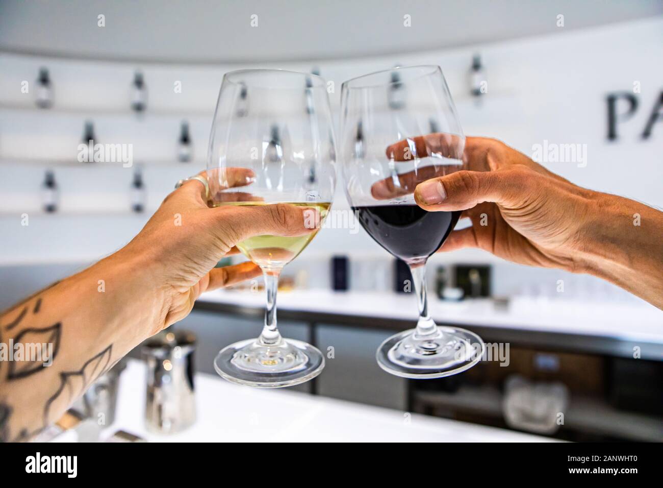 white and red wine glasses cheering selective focus against white interior design bar counter of