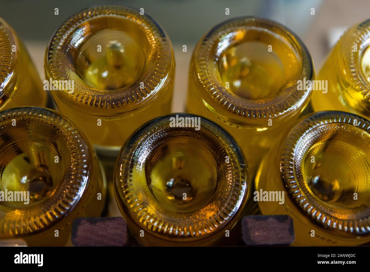 a lot of amber color glass empty wine bottles bottom close up view, with a punt at the base, winery bottling line concept background Stock Photo