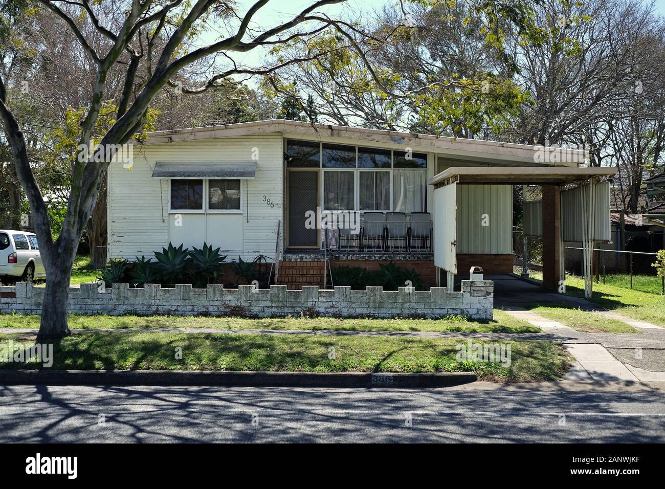 Low set 50s 60s suburban house weatherboard walls front patio and picture window, low masonry ...