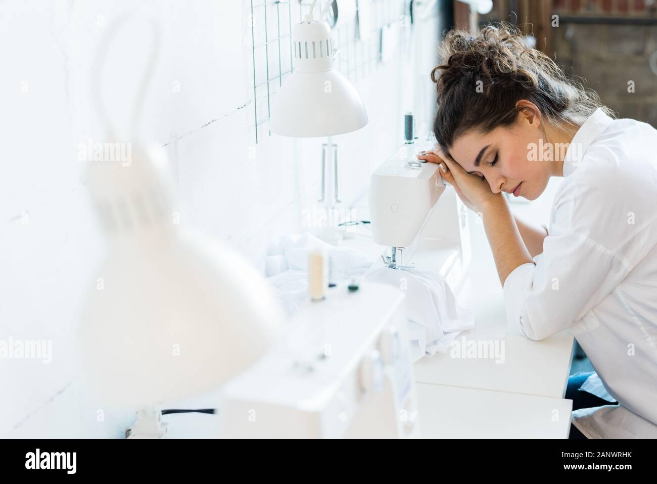 Tired seamstress at workplace Stock Photo