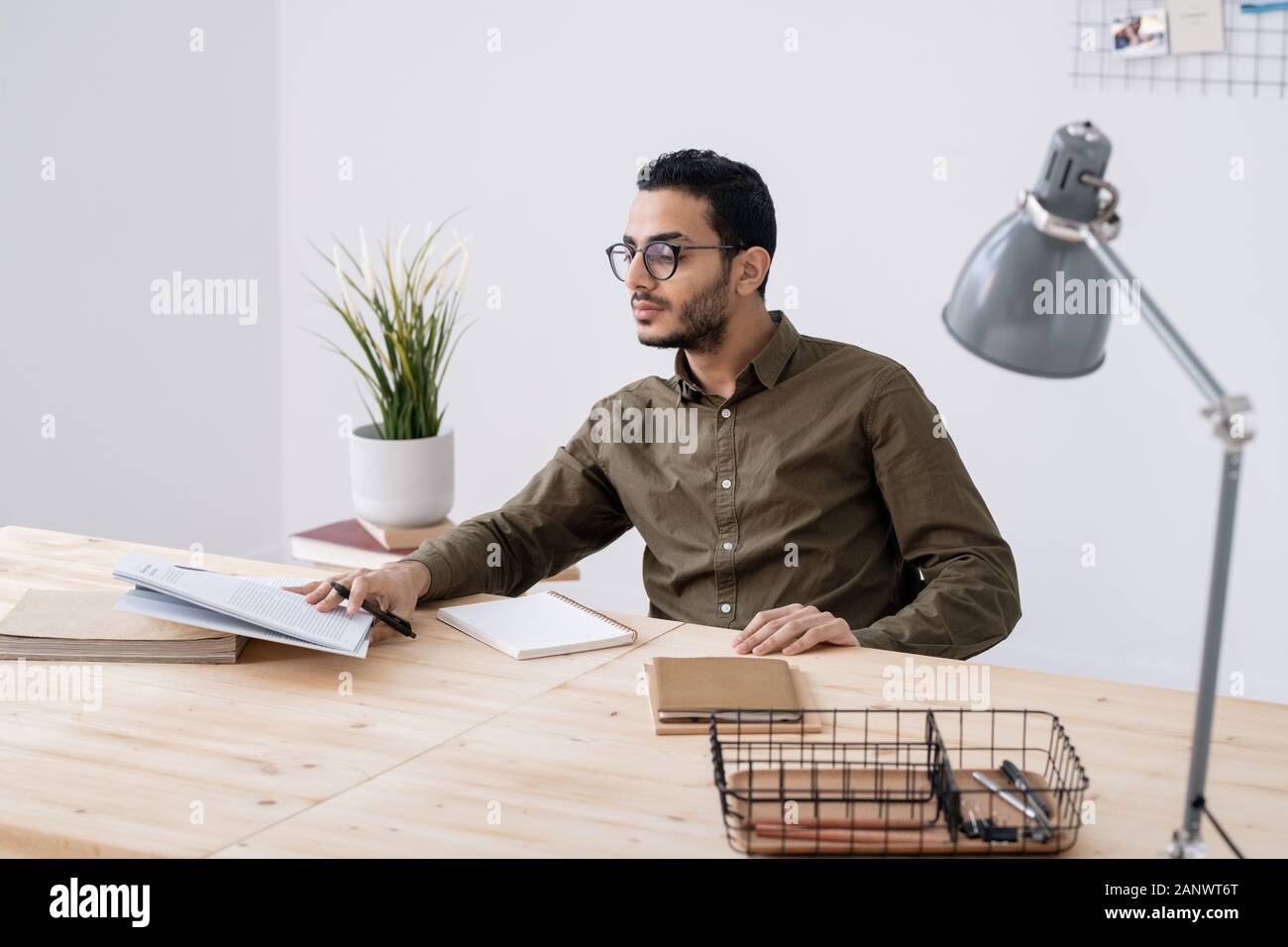 Young male student in eyeglasses looking at his notes in notepad Stock ...