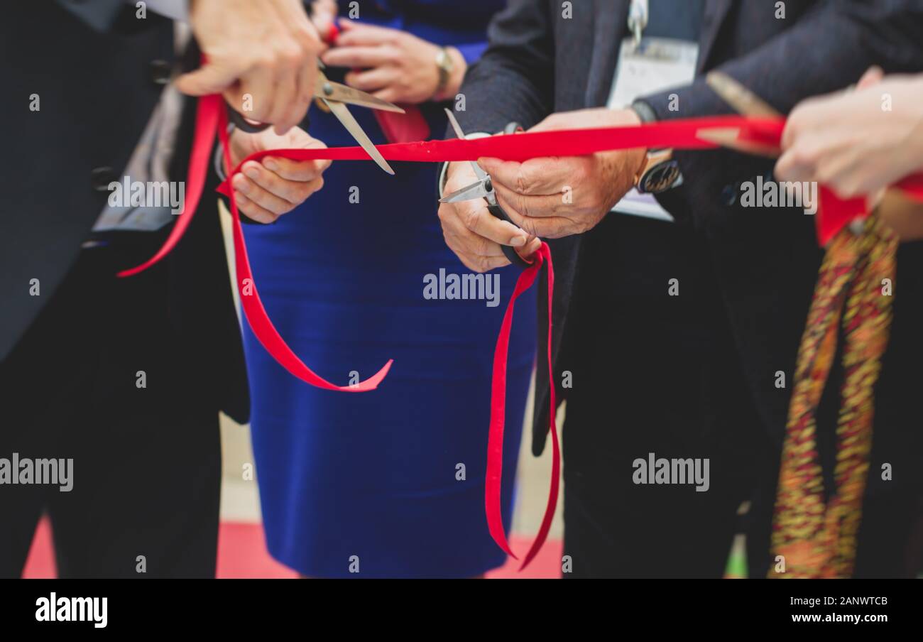 Process of cutting the red ribbon during the grand opening of the new