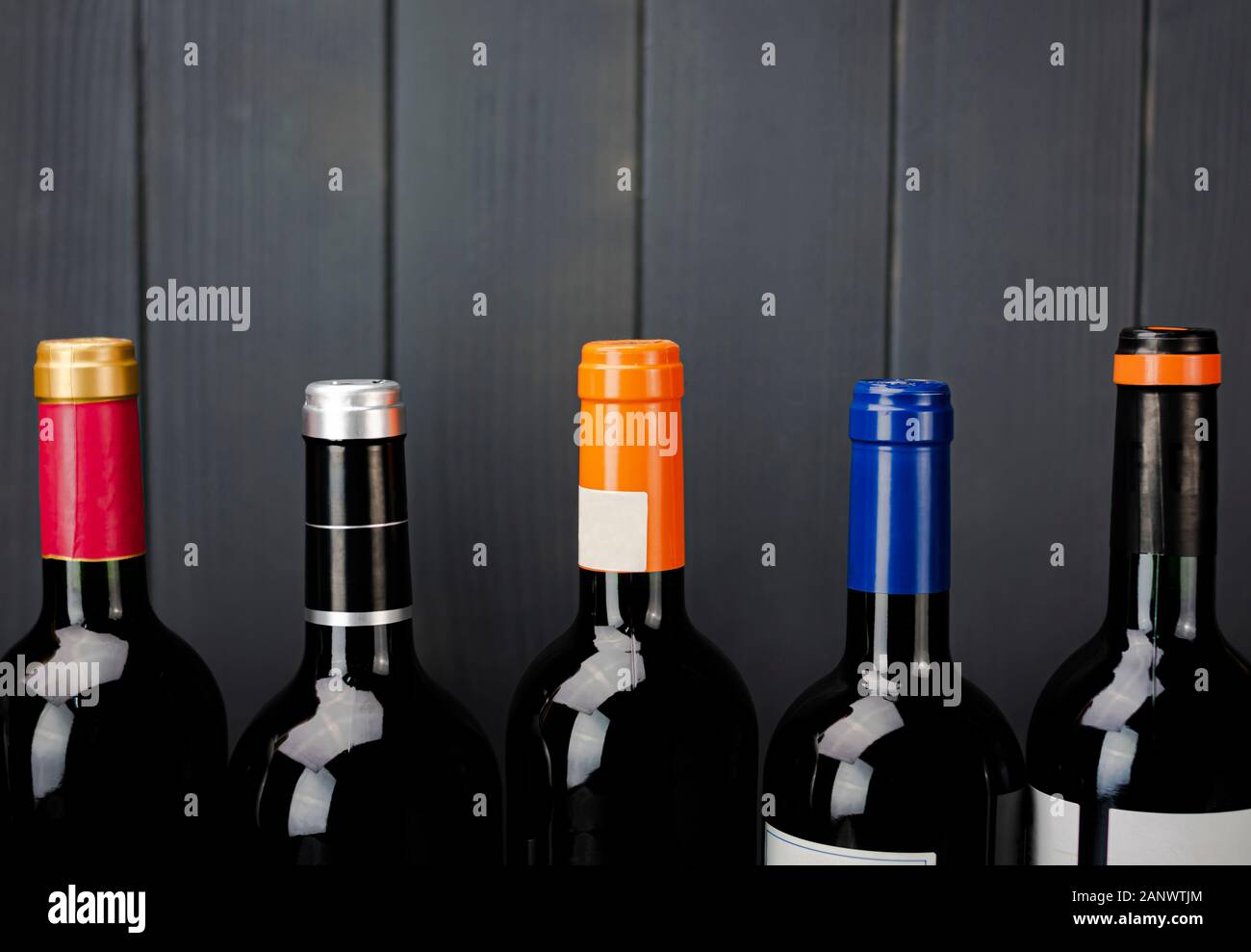 Bottles of red wine from different manufacturers with unopened colored labels in vertical arrangement Stock Photo