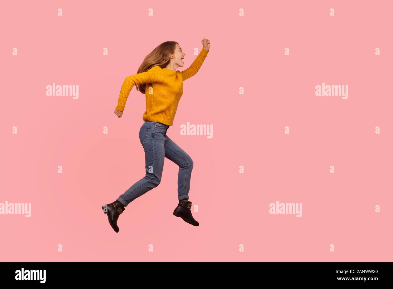 Full length portrait of excited ginger girl in sweater and denim jumping in air or flying up, running rushing somewhere, energetic and enthusiasm scre Stock Photo