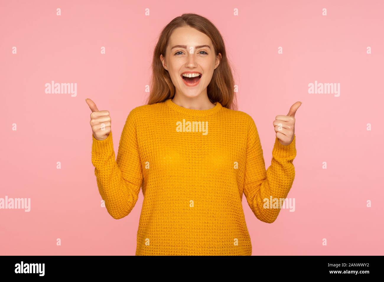 Thumbs up! Portrait of attractive cheerful ginger girl in sweater doing like gesture with finger up, expressing approval, customer showing excellent f Stock Photo