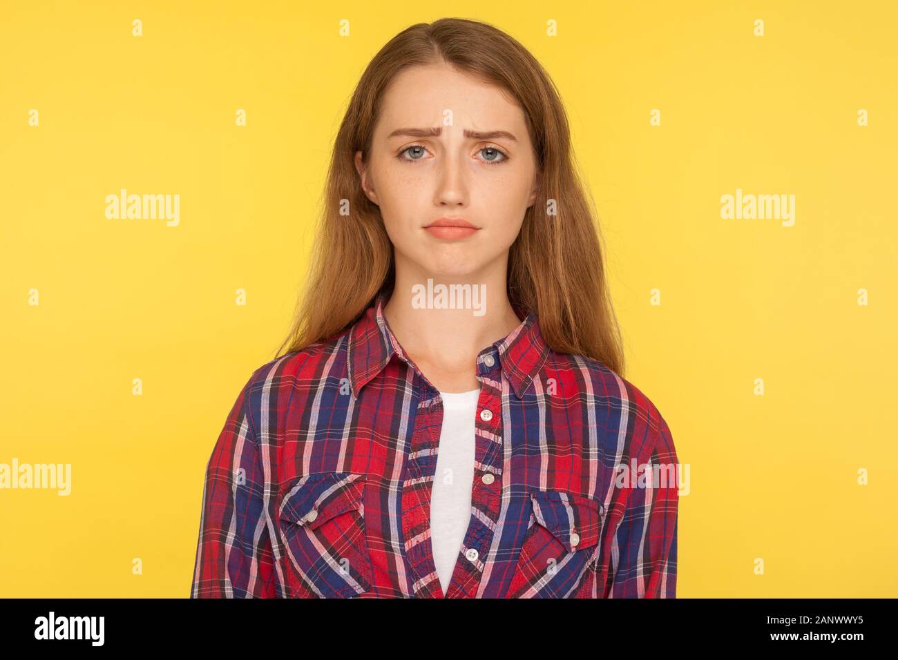 Portrait of unhappy ginger girl in checkered shirt frowning and looking at camera with upset dismal expression, feeling insulted, resentful facial emo Stock Photo