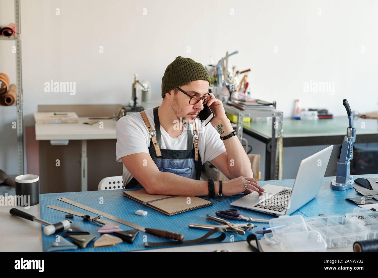 Leatherworker calling client Stock Photo