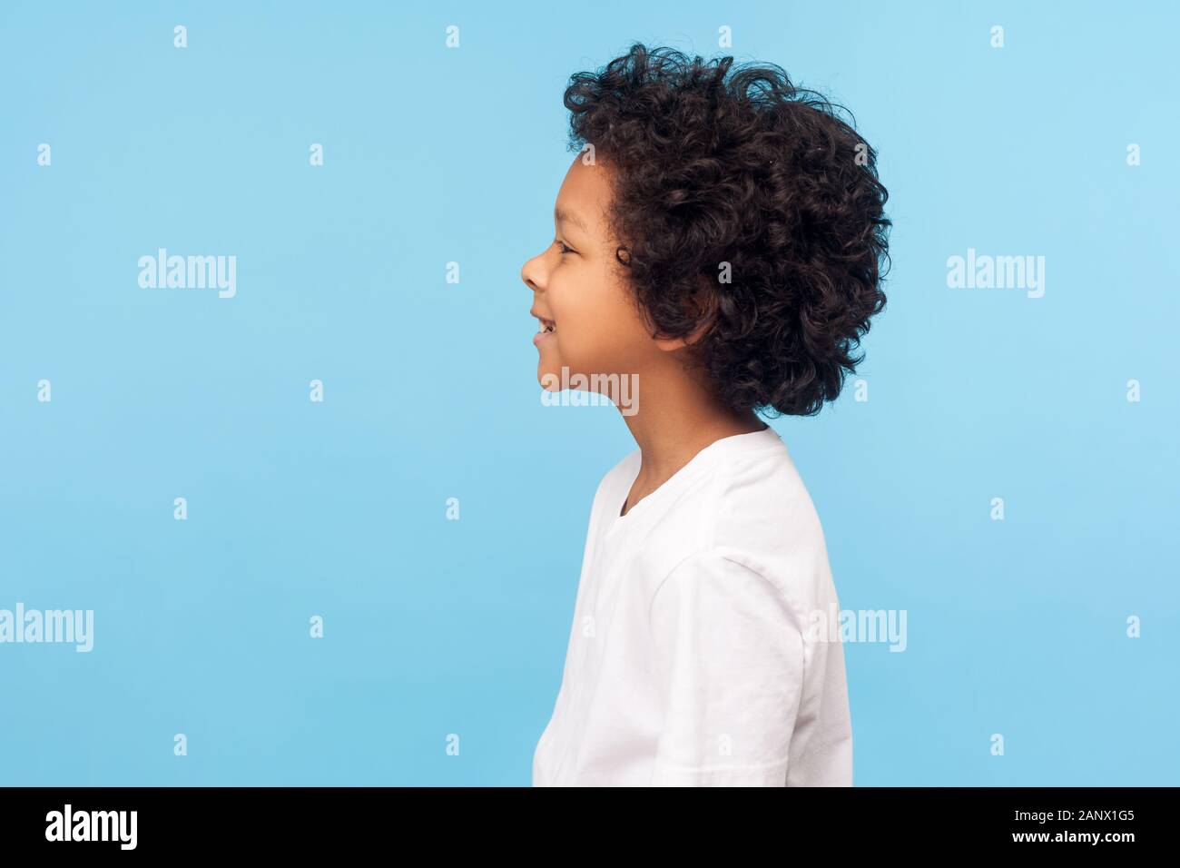 Profile Of Happy Little Boy With Curly Hair In T Shirt Smiling Carefree And Looking To Side Copy Space Healthy Cheerful Child With Positive Emotions Stock Photo Alamy