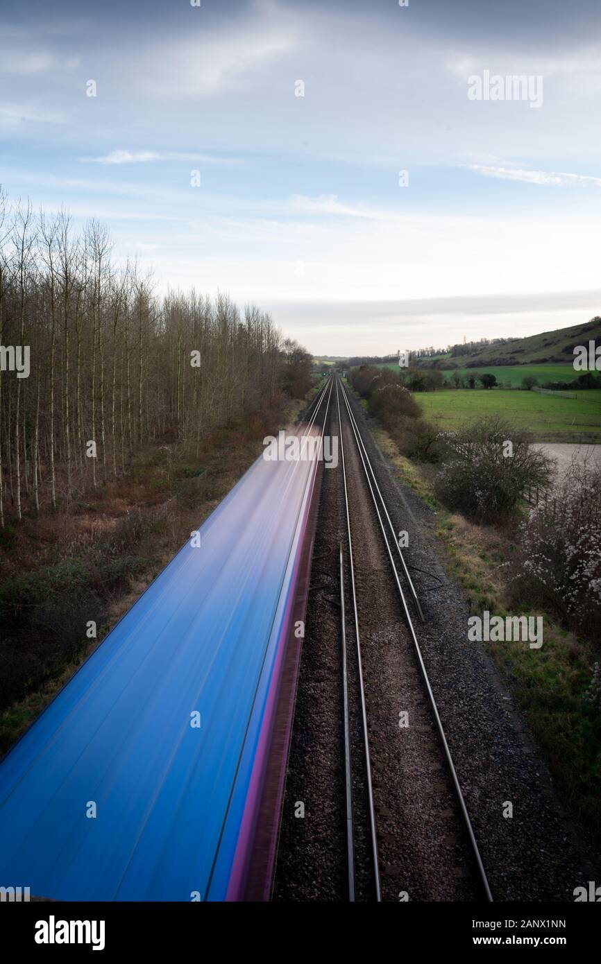 A moving train on straight tracks in the English Countryside Stock Photo