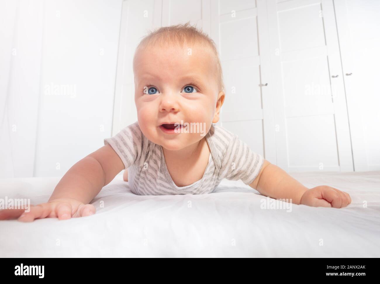 Cute little baby boy toddler learn to crawl view from low angle smiling to camera Stock Photo