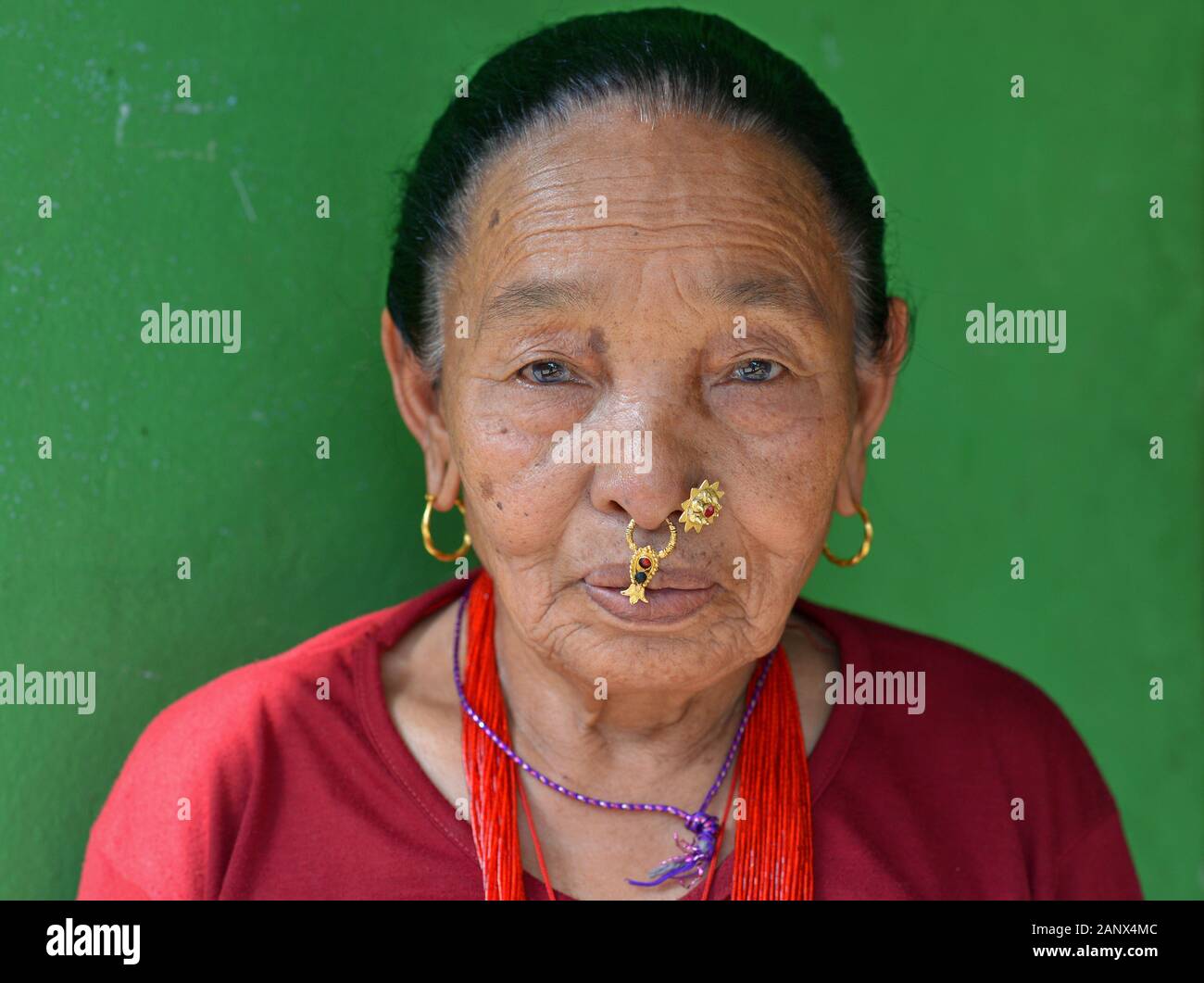 Elderly Nepali Magar woman with traditional nose jewelry poses for the camera. Stock Photo
