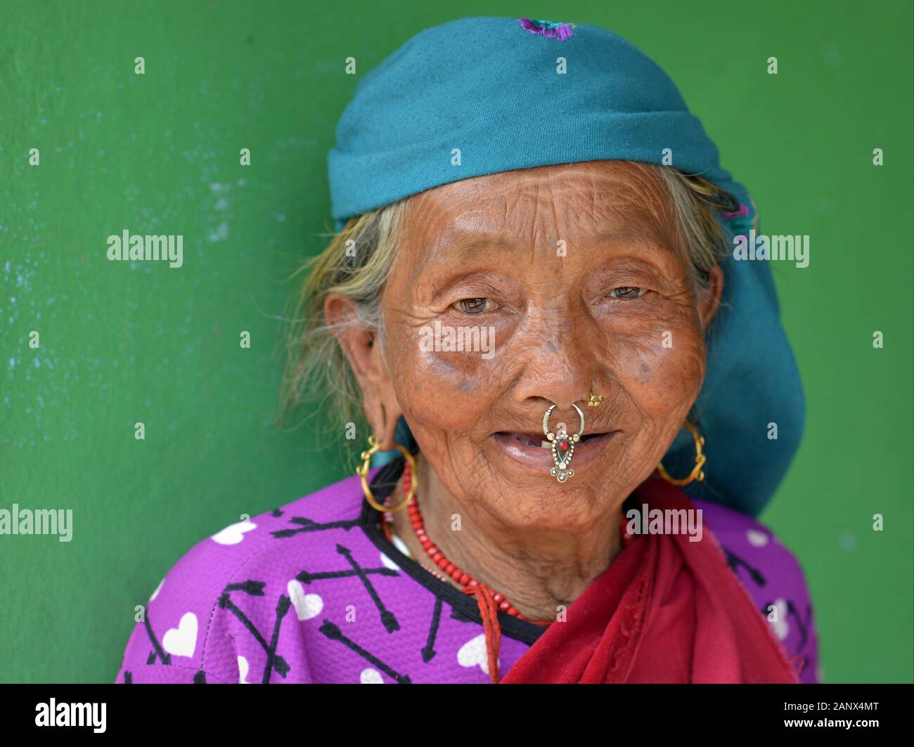 Old Nepali Magar woman with traditional nose jewelry poses for the camera. Stock Photo