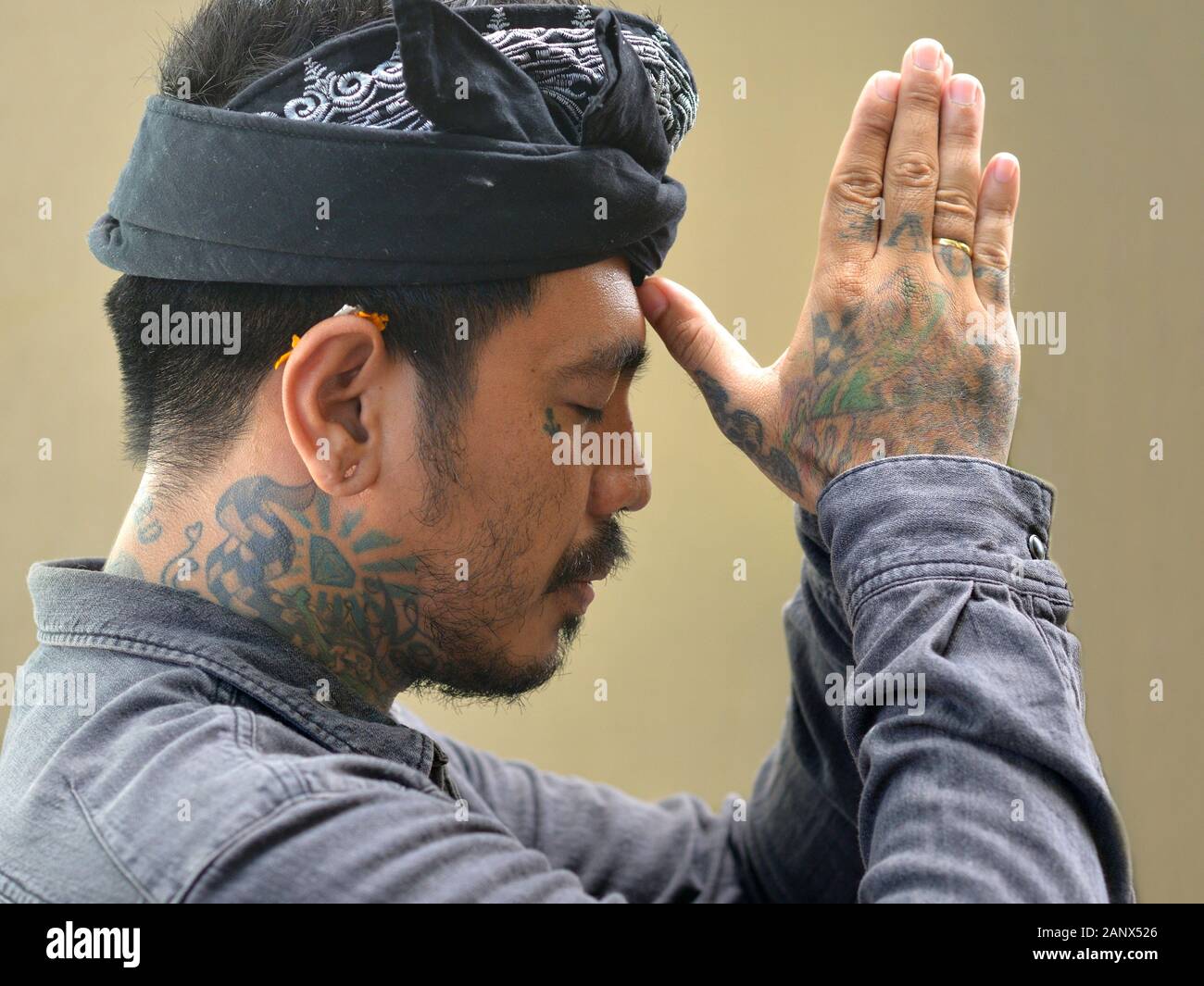 Young Balinese tattoo artist prays to the Hindu gods. Stock Photo