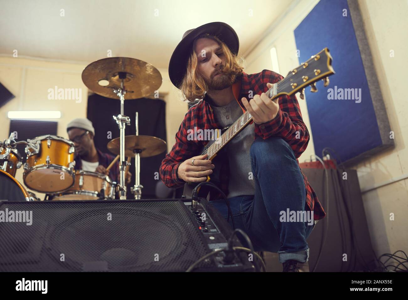 Low Angle Portrait Of Contemporary Long Haired Musician Setting Up