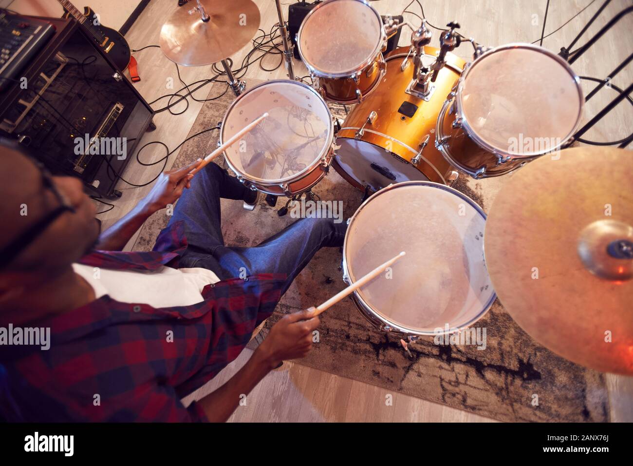 High angle portrait of young African-American man playing drums with contemporary music band during rehearsal or concert in studio, copy space Stock Photo