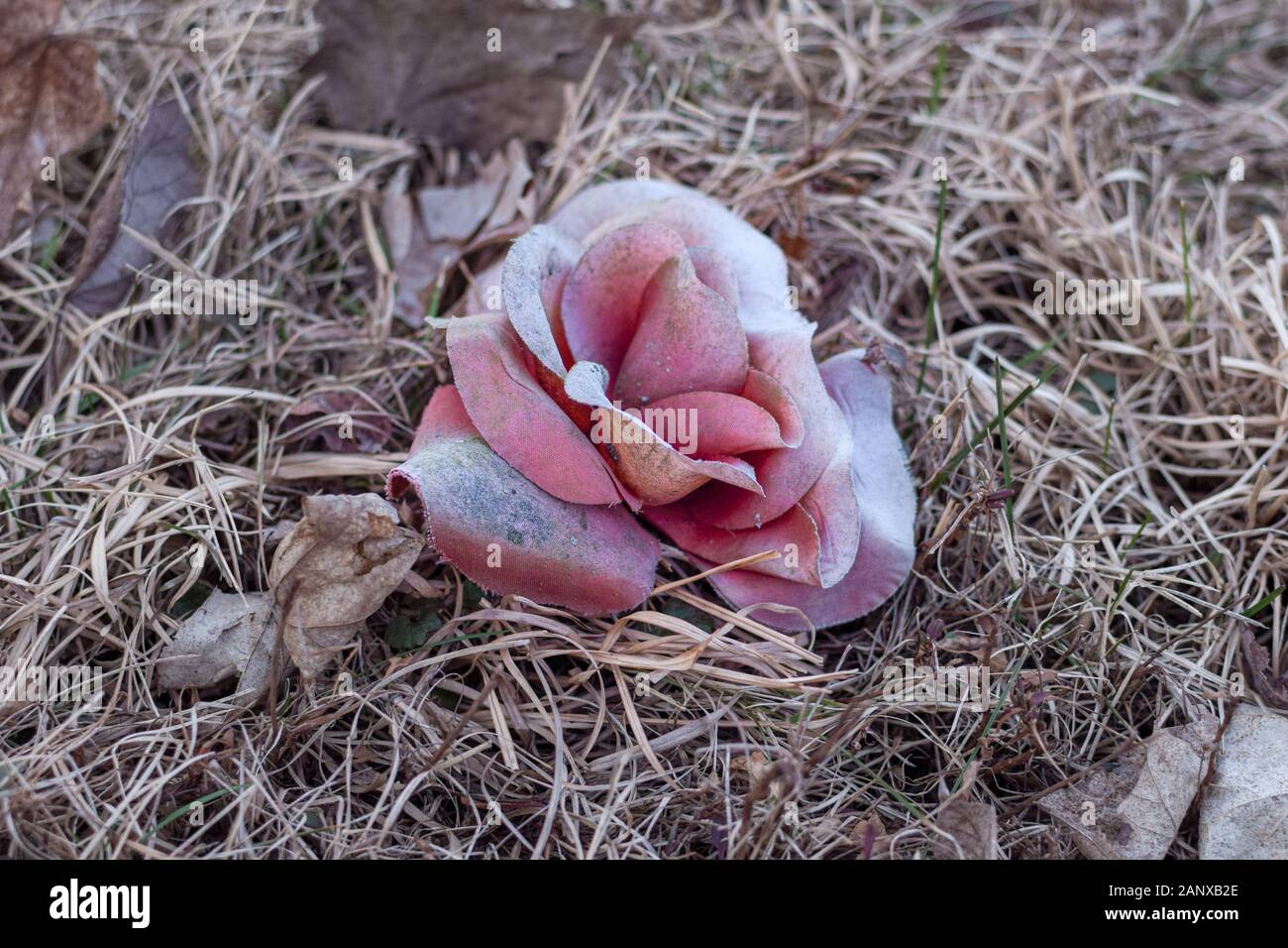 Closeup of an old dirty fake flower at an old delapidated looking graveyard on a gray gloomy day