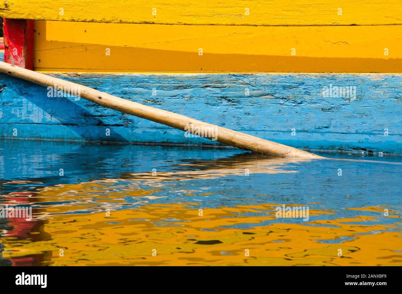 Colorful frame: detail of yellow, blue and red Trajinera boat and its reflection, in Xochimilco, Mexico Stock Photo