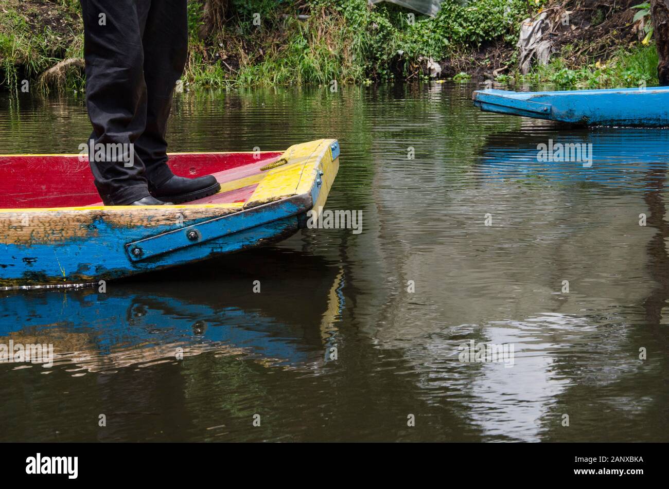 Xochimilco, Mexico; legs of a man at the end of a trajinera boat. Colorful and traditional scene. Stock Photo
