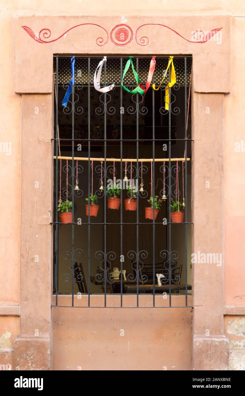 Nice window with colored ribbons, bells and small plants in a street in downtown Santiago de Queretaro, Mexico Stock Photo