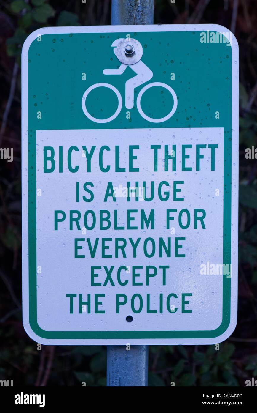A View of green road sign with bushes in the backgroung in Vancouver. 'Bicycle theft is a huge Problem for everyone except the police'. Stock Photo