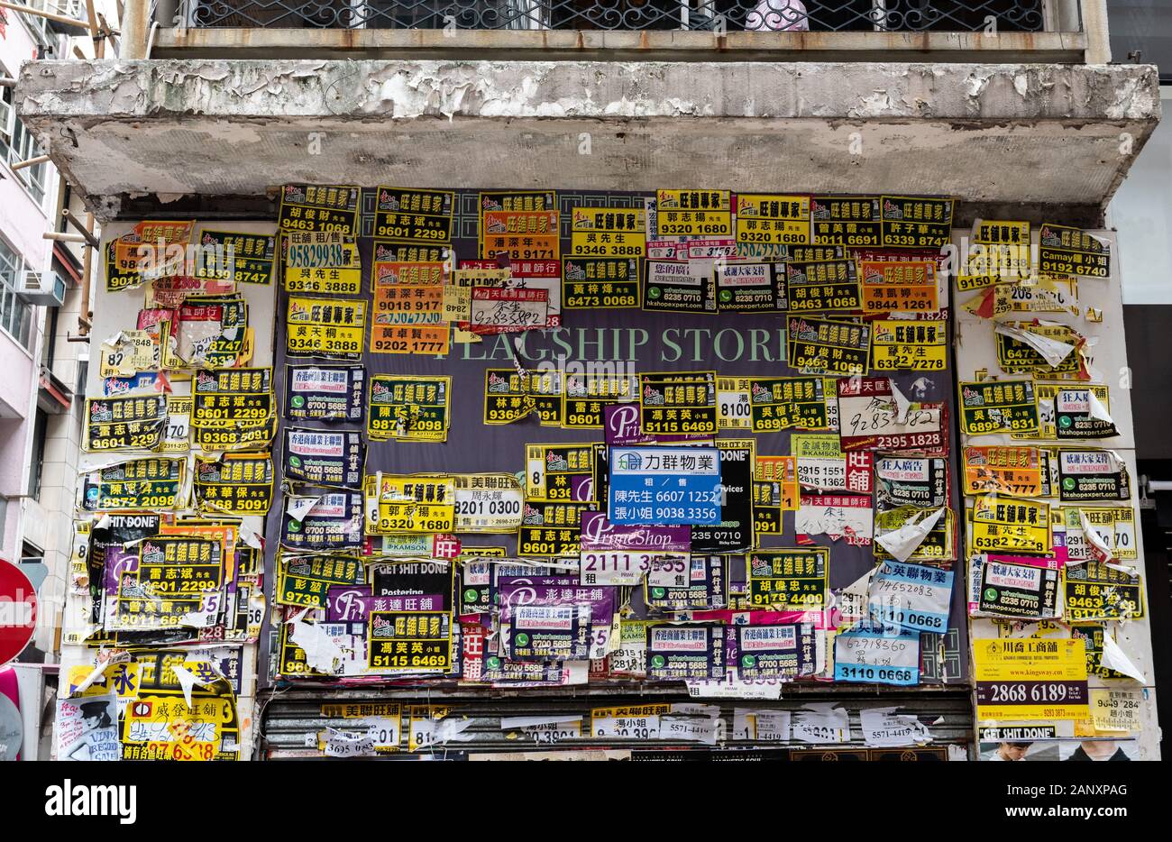 A recently closed handbag shop front is plastered with estate agent advertisements. Businesses in Hong Kong suffer regularly being forced to shut as l Stock Photo